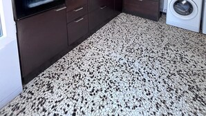 Cozinha compacta com armários escuros, forno embutido, pia e máquina de lavar roupa.
