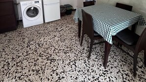 Cozinha compacta com máquina de lavar, geladeira e área de jantar com toalha de mesa xadrez.