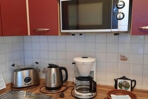 A kitchen with a microwave, toaster, kettle, and coffee maker on the counter. - Eismann Holiday Home (Auerbach OT Schnarrtanne)