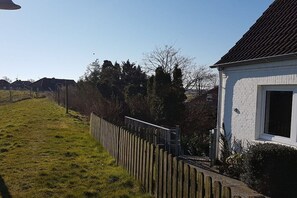 Ein Wohnhaus mit weißem Backsteinhaus, Holzpforte und Rasenfläche.