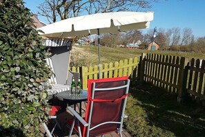 An outdoor seating area with a table, chairs, and an umbrella. - Holiday apartment with 1 bedroom (Dornumersiel)