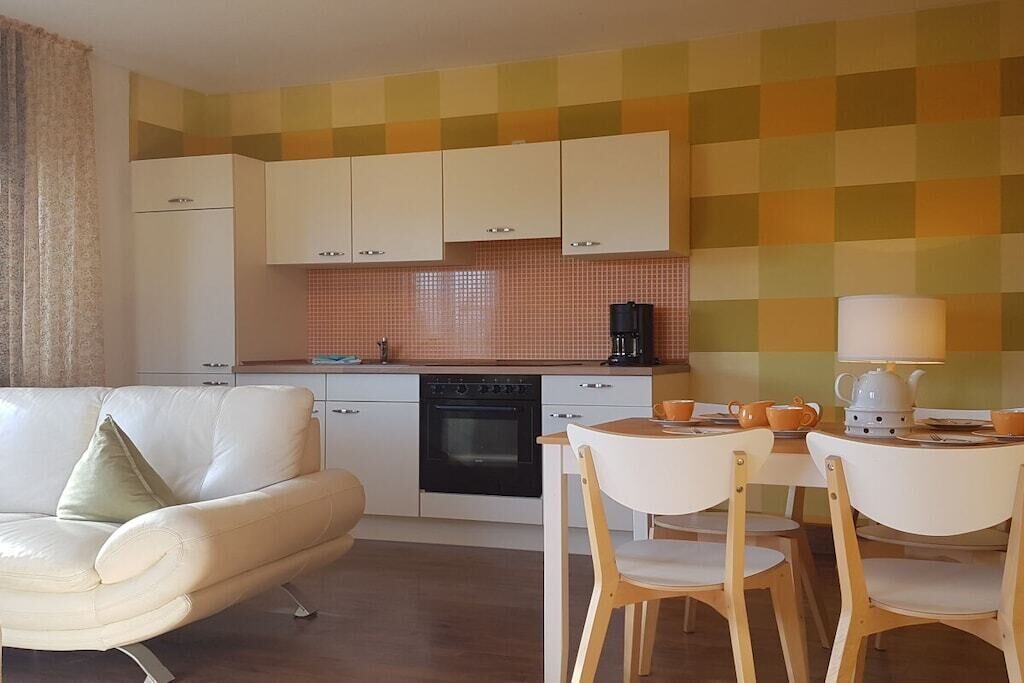 A compact kitchen with white cabinets, a coffee maker, and a dining area with a table and chairs.