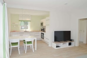 Un espace de vie moderne comprenant un coin repas, une kitchenette et un téléviseur à écran plat.