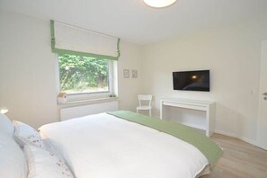 Une chambre à coucher comprenant un lit, une télévision, une chaise et une fenêtre donnant sur un paysage verdoyant.