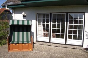 A building with a large garage door and a small wooden structure with a striped awning. - Holiday apartment with 2 bedrooms (Friedrichskoog)