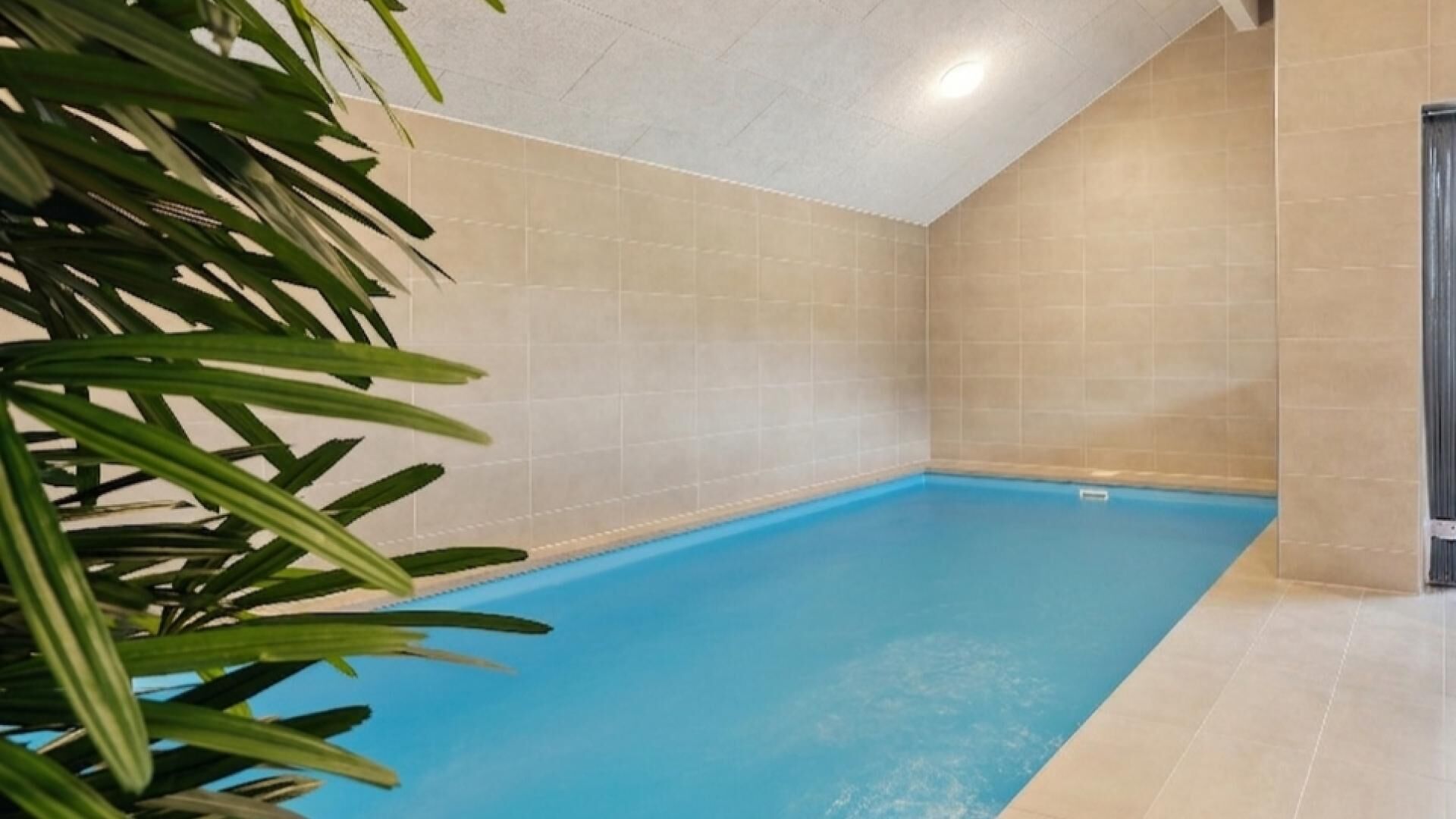 A swimming pool with tiled walls and a ceiling light fixture.