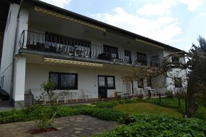 Un bâtiment à deux étages doté d’un balcon, d’un espace extérieur aménagé pour s’asseoir et d’un jardin.