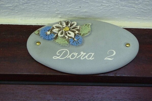 Une plaque de nom grise portant l’inscription « Dora 2 » et ornée de motifs floraux.