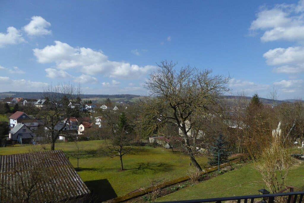 Ländliche Landschaft mit Häusern, einer Wiese und blauem Himmel.