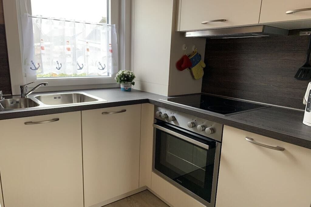 Una cocina con ventana, electrodomésticos de acero inoxidable y una pequeña planta en la encimera.