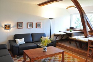 Ett mysigt vardagsrum med en soffa, ett soffbord med en vas och en matplats med ett bord och stolar.