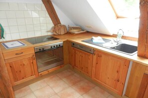 A kitchen with wooden cabinets, a stove, oven, and a sink. - Holiday apartment Forsthaus in Biestorf (Malchow OT Biestorf)