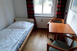 A small room with a single bed, a wooden table, and a chair. - Holiday apartment Forsthaus in Biestorf (Malchow OT Biestorf)