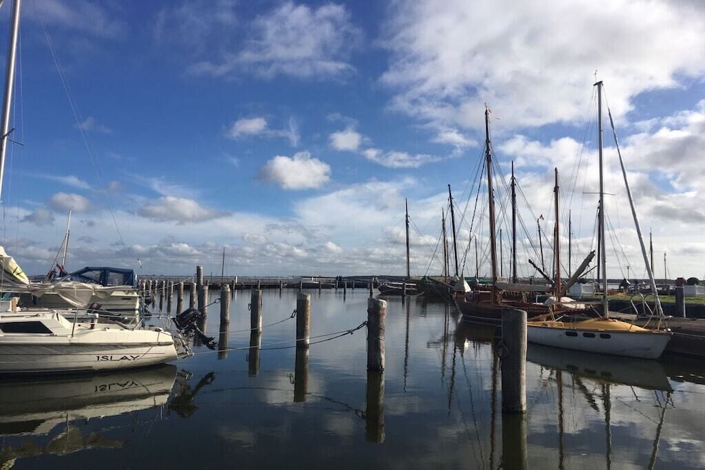 Ein Yachthafen mit mehreren vertäuten Booten, ruhigem Wasser und klarem Himmel.
