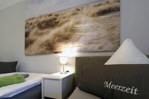 A hotel room with a bed, a nightstand with a lamp, and a wall-mounted artwork. - Holiday apartment with 1 bedroom (Dierhagen)
