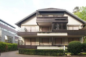 A two-story residential building with a balcony, a garage, and a well-maintained garden. - Holiday apartment with 2 bedrooms (Timmendorfer Strand)