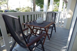 A wooden deck with two chairs and a table, a white lantern, and a white railing. - Holiday apartment with 2 bedrooms (Heringsdorf)