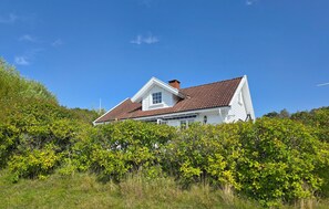 A white house with a brown roof, surrounded by green foliage. - 3 bedroom nice home in Skjærhalden (Skjærhalden)