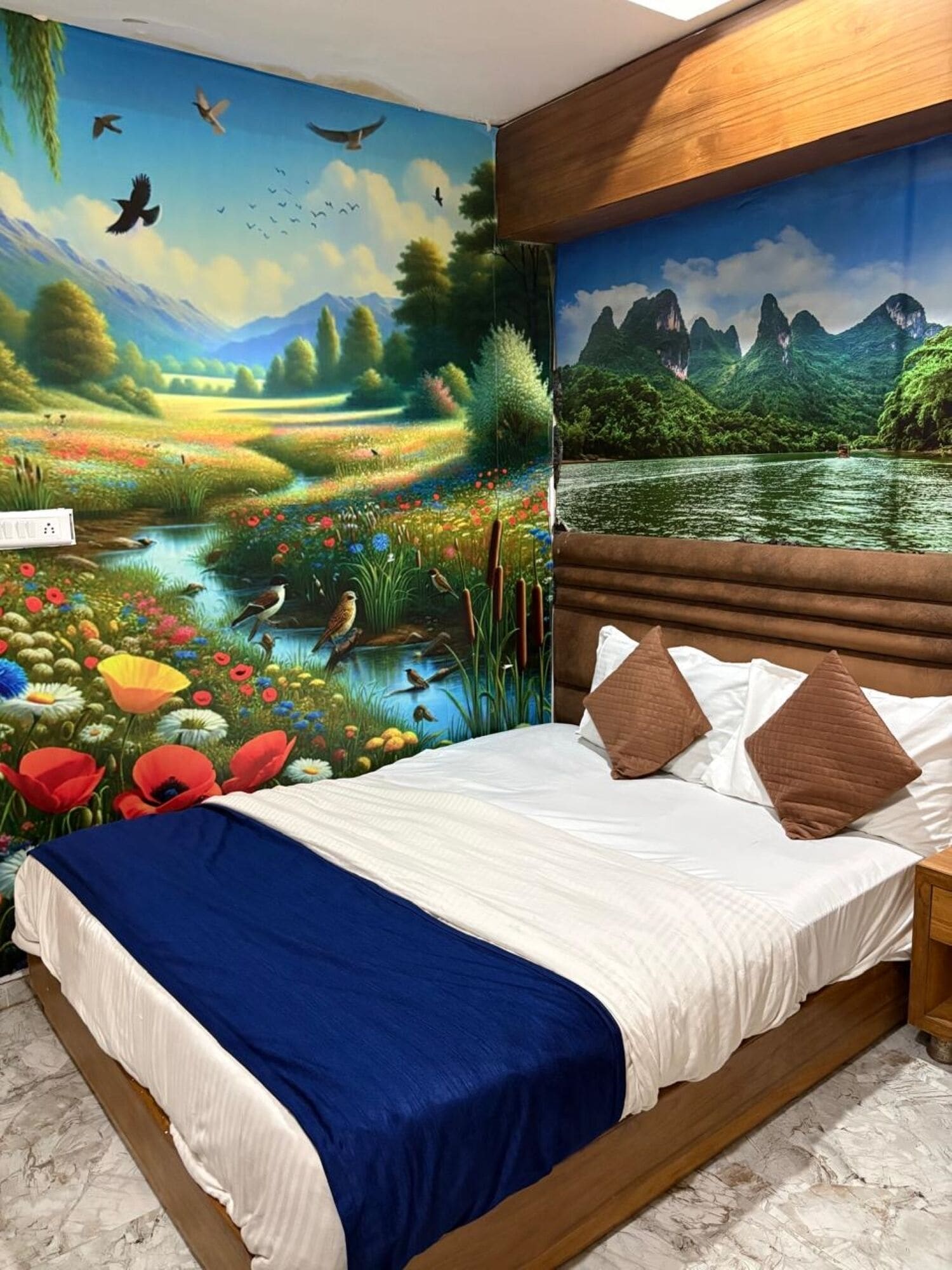 Ein Schlafzimmer mit einer Landschaftsmalerei an der Wand, einem Bett mit weißer Bettwäsche und braunen Kissen sowie einem Holz-Kopfstück.