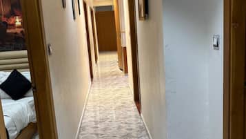 Ein Hotelgang mit Marmorboden, Holztüren und einem Bett auf der linken Seite.
