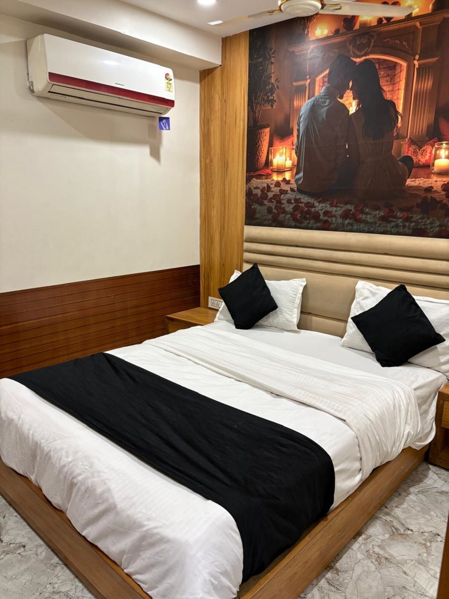 Ein Hotelzimmer mit einem Bett, einer Wand-Klimaanlage und einem großen, gerahmten Kunstwerk.