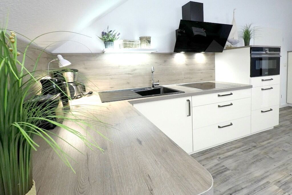 Eine moderne Küche mit einer gewölbten Arbeitsplatte, einem eingebauten Backofen und weißen Schränken.