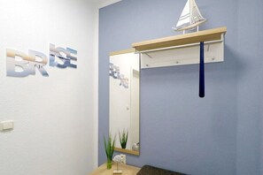 A bathroom with a mirror, a small plant, and a wooden shelf with a sailboat model. - Holiday apartment Brise (Dierhagen)