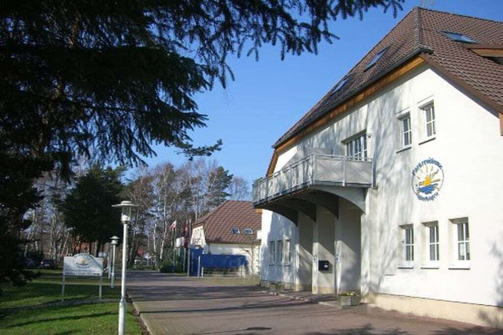En toetagers bygning med balkon og et ur på siden.