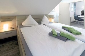 A hotel room with a bed, pillows, a nightstand, a desk, and a chair. - Holiday apartment Brise (Dierhagen)