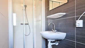 A modern bathroom with a glass-enclosed shower, a white sink, and a dark tiled wall. - Beautiful pylon OK21 (Oostkapelle)