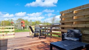 An outdoor deck with a table and chairs, surrounded by wooden fences and a clear sky. - Beautiful pylon OK21 (Oostkapelle)