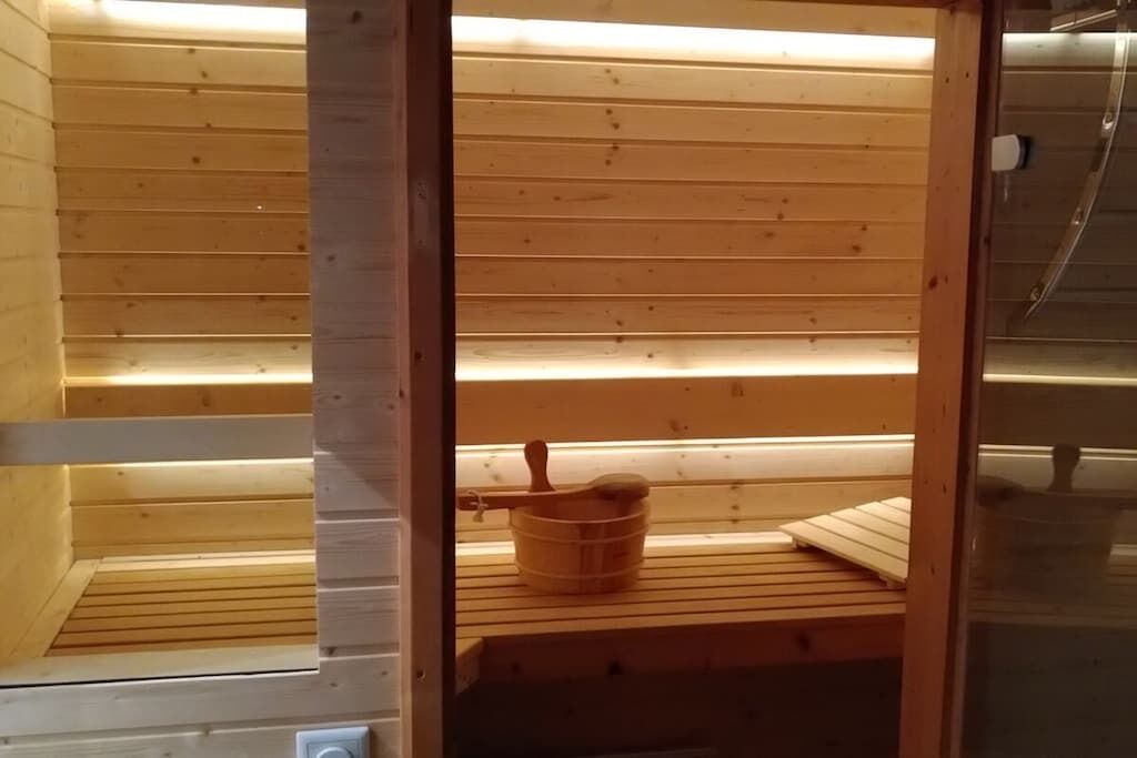 A sauna room with wooden benches and a wooden bucket.