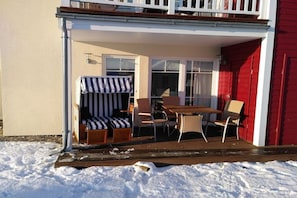 A covered outdoor seating area with a table and chairs, a striped bench, and a small sofa. - Strandnest Sierksdorf (Sierksdorf)
