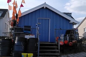 A blue building with a white door, surrounded by black barrels, orange and pink flags, and a small staircase. - Strandnest Sierksdorf (Sierksdorf)