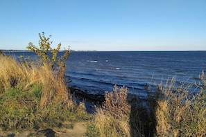 A coastal landscape with a clear sky, a body of water, and vegetation. - Strandnest Sierksdorf (Sierksdorf)