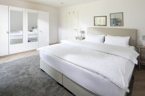 A bedroom with a large bed, a wardrobe, and a nightstand. - Oystercatchers in house Bill15 (Juist)