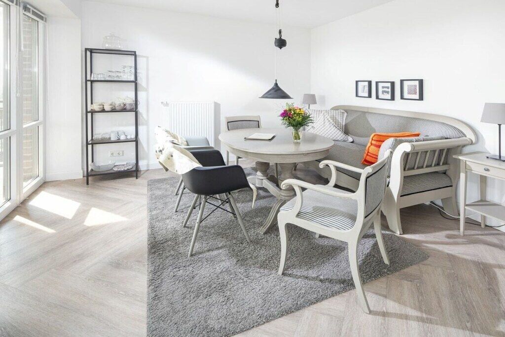 Ein modernes Wohnzimmer mit einem runden Esstisch, weißen Sofas und einer schwarzen Metallregaleinheit.