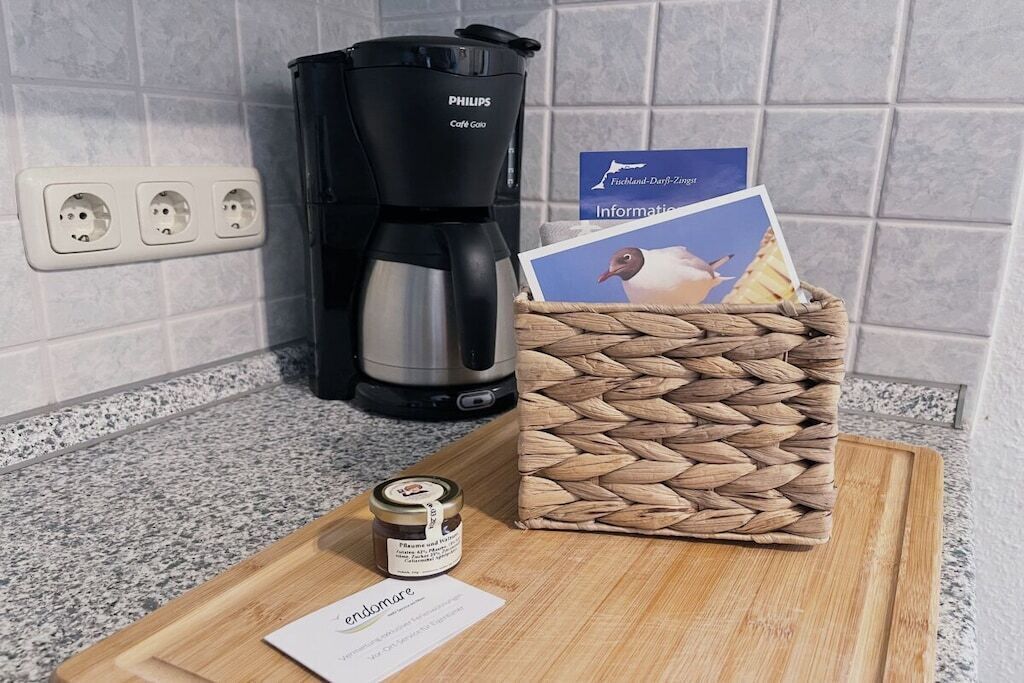 Un piano di lavoro in cucina con una macchina da caffè, un cesto di vimini, un vasetto di marmellata e un biglietto.