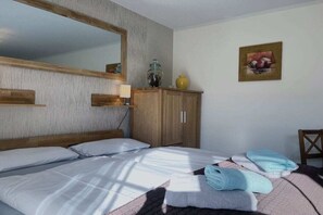 A bedroom with a bed, a wooden wardrobe, a mirror, and a painting on the wall. - Holiday apartment with 1 bedroom (Dierhagen)