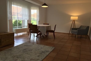 A dining area with a table and chairs, a standing lamp, and a view through a window. - Mirow Lake District Seesiedlung EC (Mirow)