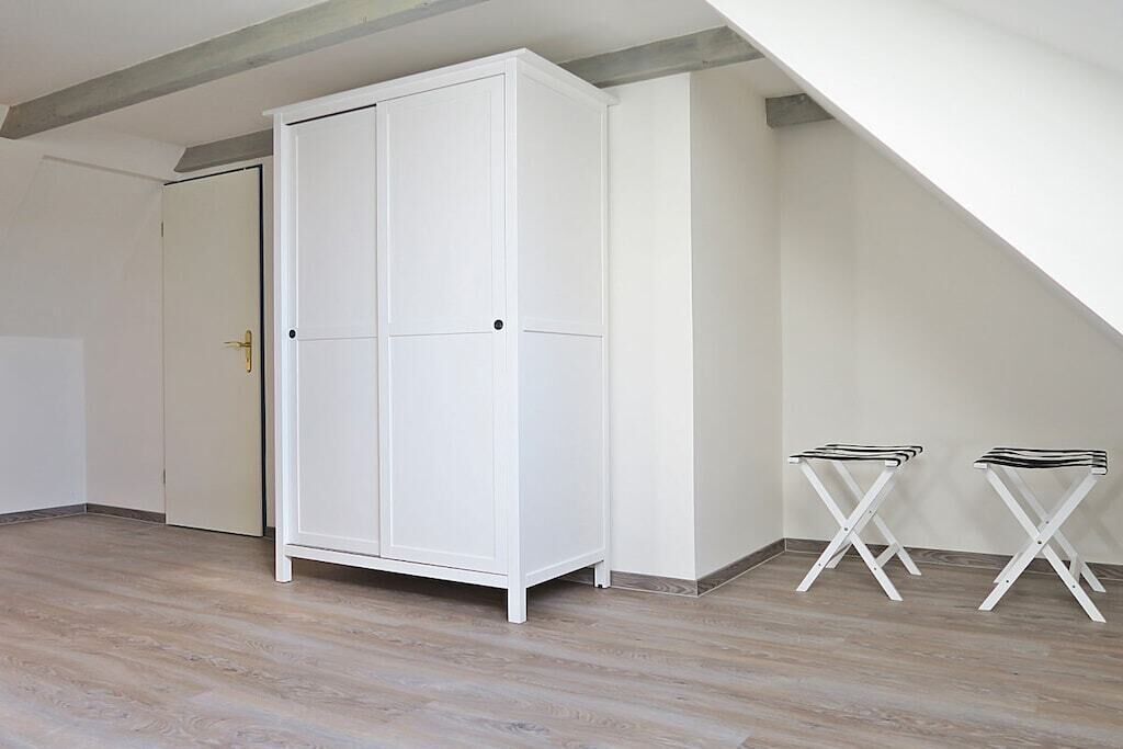 Una stanza con un armadio bianco, una porta e due sedie pieghevoli bianche.