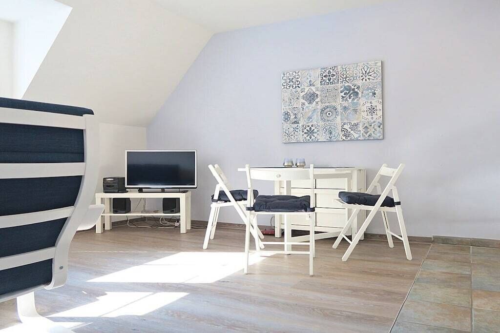 A room with a TV, white furniture, and a patterned wall.