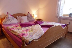 Een slaapkamer met een houten bed, bloemenbeddengoed en een nachtkastje met een lamp.