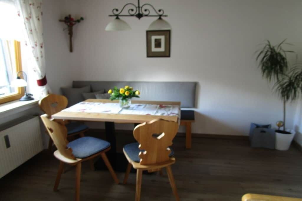 Ein Essbereich mit einem Tisch, Stühlen und einer Blumenvase.
