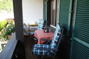 A patio with a table and chairs, a small table with a lantern, and a view of a garden. - Holiday apartment with 2 bedrooms (Farchant)