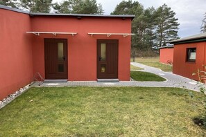 Ein rotes Gebäude mit zwei Türen und einem kleinen Rasen.