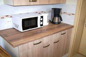 Eine Küchenzeile mit einer Mikrowelle, einer Kaffeemaschine und Holzschränken.