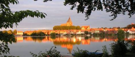 A calm lake with a church and residential buildings in the background.