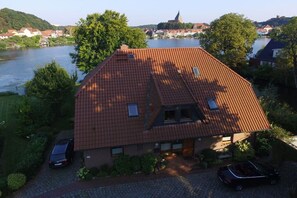 Une maison avec un toit en pente, une allée pavée et une rivière en arrière-plan.