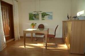 A dining area with a table, chairs, and a cabinet. There are two paintings on the wall. - Paradise on the city lake (Mölln)